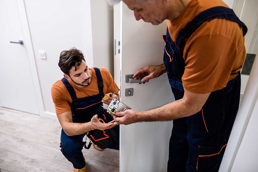 Zwei Handwerker wechseln ein Türschloss aus